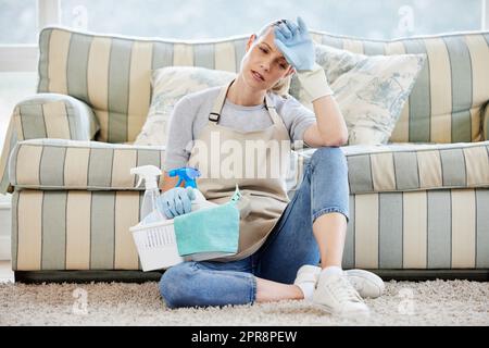 Hausarbeit... die nie endende Aufgabe. Eine junge Frau, die erschöpft aussieht, während sie zu Hause Hausarbeiten macht. Stockfoto