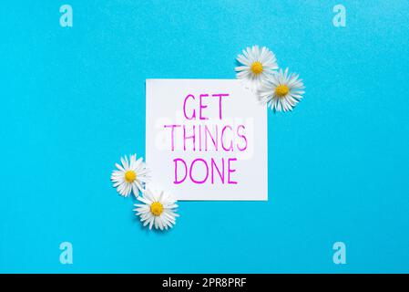 Schild mit der Anzeige „Get Things Done“. Ein Wort, auf das geschrieben wurde, um Verantwortung für die Aktion der Führungskraft zu übernehmen Haftnotiz mit wichtigen Botschaften und Blumen auf beiden Seiten. Stockfoto