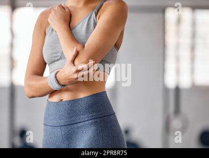 Nahaufnahme einer weißen Frau, die ihren schmerzenden Ellbogen während des Trainings in einem Fitnessstudio hielt. Sportlerin mit schmerzhafter Armverletzung durch Gelenkfraktur und Muskelentzündung während des Trainings. Schwierigkeiten mit steifen Krämpfen, die Unbehagen und Belastungen verursachen Stockfoto