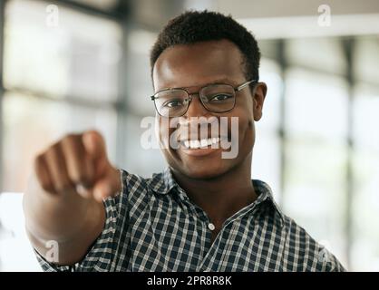 Porträt eines selbstbewussten jungen afroamerikanischen Geschäftsmanns mit Brille, die Zeigefinger auf die Kamera zeigt, während sie in einem Büro steht. HR-Manager wählt Sie Stockfoto