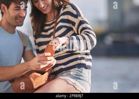 Der intelligenteste Reiseführer der Stadt. Ein junges Paar, das ein Smartphone benutzt, während es die Stadt London erkundet. Stockfoto