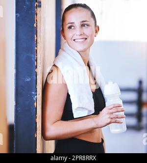 Ich fühle mich nach meiner Sitzung erfrischt. Eine sportliche junge Frau trinkt Wasser beim Training im Fitnessstudio. Stockfoto