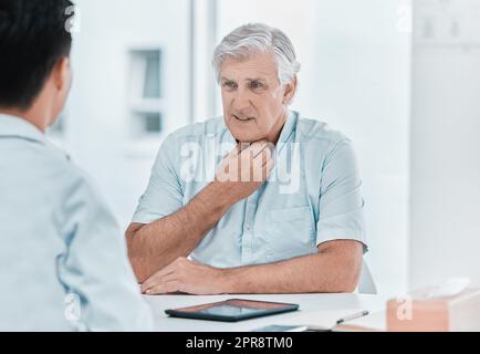 Ich hatte Schmerzen in meinem Hals. Ein reifer Mann saß mit seinem Arzt und beschwerte sich während einer Konsultation über Halsschmerzen. Stockfoto