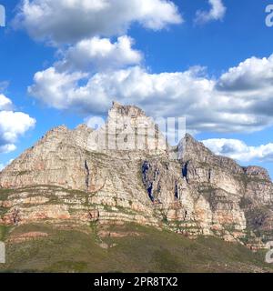 Felsige Berglandschaft mit grüner Weide vor blauem Himmel mit Copyspace. Ein beliebtes Reiseziel für Touristen und Wanderer. Blick auf den Tafelberg in Kapstadt, Westkap Stockfoto