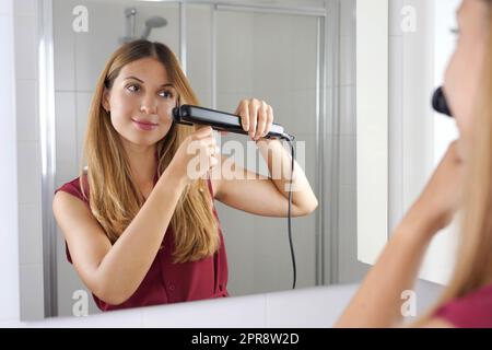 Schöne junge Frau mit Streapod für das Glätten der Haare in einer einfachen Weise zu Hause Stockfoto