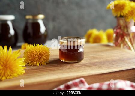 Kleines Glas Löwenzahn-Honig oder Sirup mit frischen Blumen Stockfoto