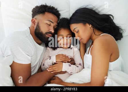 Ein Nickerchen am Tag hält die Erschöpfung fern. Eine junge Familie macht zu Hause zusammen ein Nickerchen. Stockfoto