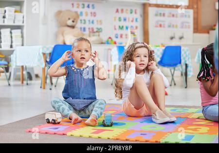 Dieses Lied lehrt uns über all unsere Körperteile. Zwei kleine Mädchen sitzen nebeneinander in der Klasse. Stockfoto