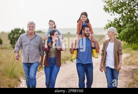 Dies ist unsere Familie und der Bauernhof ist unser Zuhause. Eine Familie mit mehreren Generationen, die gemeinsam auf einem Bauernhof spazieren geht. Stockfoto