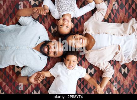 Porträt einer gemischten Familie, die zu Hause auf dem Boden liegt. Hispanische Familie, die sich zu Hause auf dem Boden auflegt Stockfoto