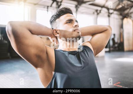 Fokussierter Sportler, der im Fitnessstudio Sit-ups macht. Bodybuilder, der im Fitnessstudio an bauchmuskeln und Rumpfteilen arbeitet. Junger, seriöser Trainer, der seine Übungsroutine im Fitnessstudio macht. Muskeltrainer im Fitnessstudio Stockfoto