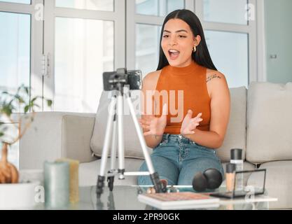 Ihr Beauty-Vlog geht los. Eine attraktive junge Beauty-Influencerin streamt live aus ihrem Wohnzimmer zu Hause. Stockfoto