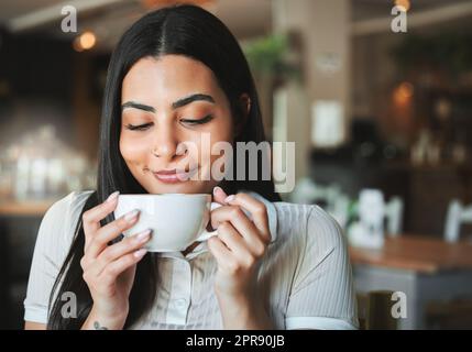 Das perfekte Gebräu. Eine junge Frau genießt eine Tasse Kaffee in einem Café. Stockfoto