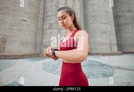 Wie bin ich für die Zeit. Eine attraktive junge Sportlerin überprüft ihre Uhr, während sie draußen läuft. Stockfoto