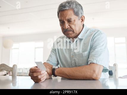 Will I Bis bald. ein älterer Mann, der unglücklich aussieht, während er zu Hause ein Foto ansieht. Stockfoto