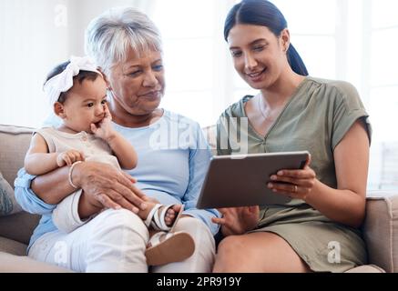 In den Armen von Nana. Eine reife Frau, die sich mit ihrer Tochter und Enkelin auf dem Sofa verklebt. Stockfoto