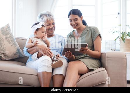 Eine reife Frau, die sich mit ihrer Tochter und Enkelin auf dem Sofa verklebt. Stockfoto