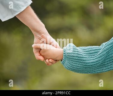 Das Leben kommt nicht mit einem Handbuch, es kommt mit einer Mutter. Eine Frau hält ihre Töchter Hand, während sie draußen geht. Stockfoto