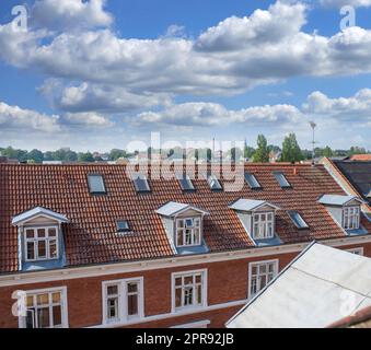 Oldwindow (Oldwindow). Blick von der Dachterrasse auf Gebäude in einer Stadt mit Glasfenstern und Rahmen unter einem wolkigen blauen Himmel. Wunderschöne Landschaftsarchitektur mit Wolken rund um eine städtische Vorstadtumgebung. Stockfoto