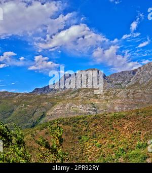 Schöner Berg in friedlicher felsiger Landschaft an einem sonnigen Tag in Kapstadt. Lebhaftes Land mit üppig grünen Büschen und Pflanzen, die in Harmonie in der Natur wachsen. Entspannende, beruhigende Aussicht auf Südafrika Stockfoto