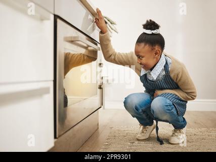 Wie viel länger. Ein kleines Mädchen beobachtet ihre Backwaren kochen im Ofen zu Hause. Stockfoto