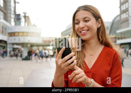 Nahaufnahme einer jungen Frau, die auf dem Berliner Stadtplatz ein Mobiltelefon benutzt Stockfoto