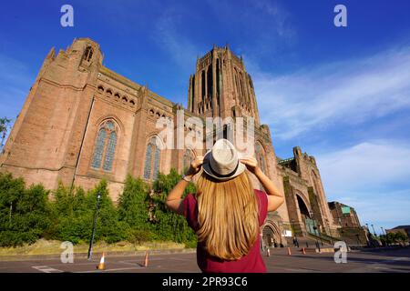 Rückansicht eines Touristen-Mädchens mit Blick auf die Cathedral Church of Christ gegen den blauen Himmel in Liverpool bei Sonnenuntergang, Großbritannien Stockfoto