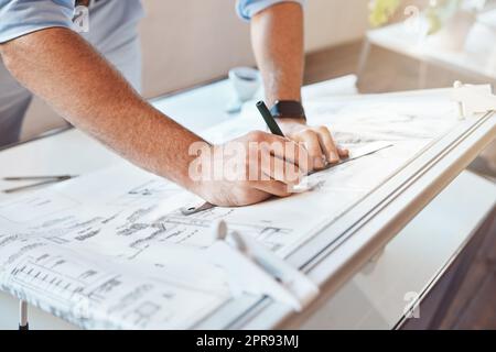 Männlicher Architekt zeichnet Bauprojekt oder Bauplan auf einem Bürotisch. Nahaufnahme eines weißen Mannes, der Messnotizen macht, skizziert und Korrekturen an einem Bauplan vornimmt. Stockfoto