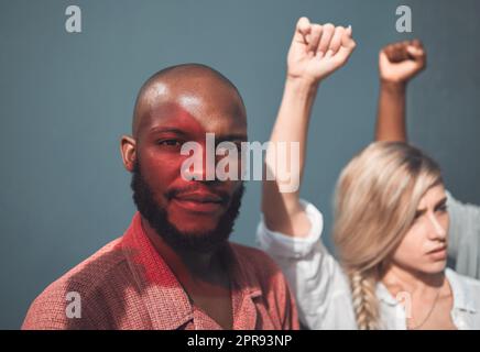 Portrait eines jungen afroamerikanischen Mannes, der mit Demonstranten zusammensteht, Fäuste hält und eine starke, eindrucksvolle Geste zur Unterstützung der sozialen Gerechtigkeit zeigt, steht die Bewegung für Menschenrechtsfragen in Einigkeit Stockfoto