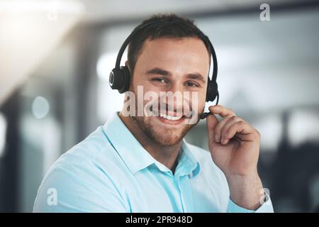 Rufen Sie uns an, wenn Sie Hilfe benötigen. Ein junger Callcenter-Agent sitzt allein in seinem Büro. Stockfoto