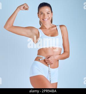 Auf Wiedersehen Körperfett. Eine junge Frau, die im Studio steht und nach dem Training ihren Bauch mit einem Maßband misst. Stockfoto