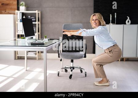 Eine Frau, Die Im Büro Yoga-Training Macht, Sitzt Auf Und Dehnt Sich Stockfoto