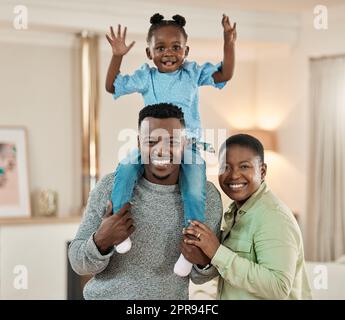 Sie sind mein Liebling, weil sie mir gehören. Verkürztes Porträt eines gutaussehenden jungen Mannes, der seinen Sohn auf den Schultern trägt, im Wohnzimmer zu Hause, mit mom in der Nähe. Stockfoto