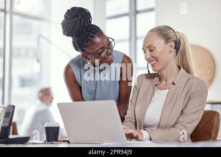 Zwei junge Frauen, die Headsets und Laptops in einem modernen Büro verwenden. Stockfoto