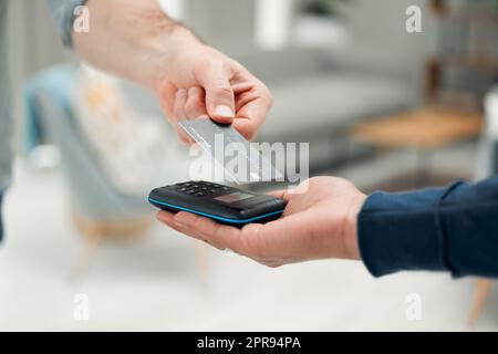 So einfach wie ein Antippen. Nahaufnahme eines nicht erkennbaren Mannes, der seine Rechnungen über einen drahtlosen Kartenleser bezahlt. Stockfoto