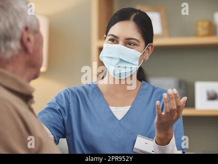 Ihre oberste Priorität ist das Gesundheitswesen. Eine junge Krankenschwester, die zu Hause eine Untersuchung mit einer älteren Patientin macht. Stockfoto