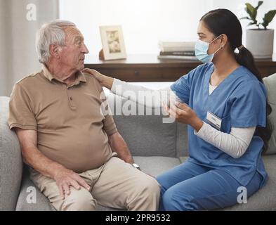 Shes bekam den besten Rat. Eine junge Krankenschwester, die zu Hause eine Untersuchung mit einem älteren Patienten machte. Stockfoto