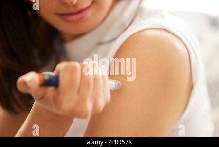 Leben mit Diabetes. Nahaufnahme einer unkenntlichen Frau, die sich zu Hause mit Insulin in den Arm spritzt. Stockfoto