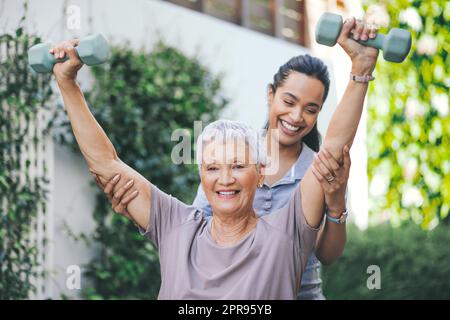 Ein Frühaufsteher fängt den Wurm. Eine ältere Frau hebt während einer Sitzung mit einem Physiotherapeuten Hanteln. Stockfoto