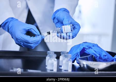 Vorbereitung auf die Impfung. Ein nicht erkennbarer Wissenschaftler, der eine Spritze verwendet, um den covid 19-Impfstoff aus einer Flasche im Labor zu extrahieren. Stockfoto