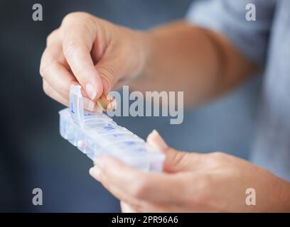 Dies hilft mir, auf meinem Medikamentenplan zu bleiben. Eine ältere Frau hält ihre wöchentliche Pillenbox. Stockfoto