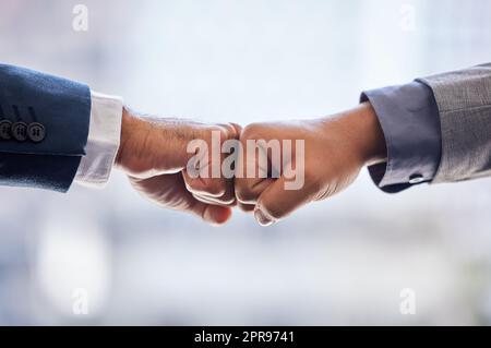 Zwei nicht erkennbare Geschäftsleute stehen zusammen und geben sich im Büro einen Faustschlag. Stockfoto