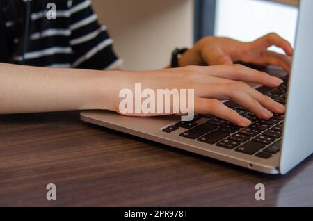 Nahaufnahme Hand Mädchen Eingabe Tastatur Computer Laptop digitale Online-Netzwerk Kommunikation Internet auf dem Tisch. Stockfoto