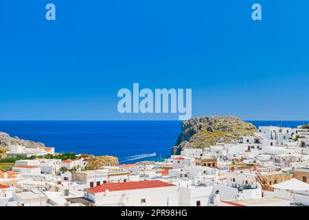 Blick auf die Stadt Lindos und das smaragdgrüne Meer mit vorbeifahrenden Booten, die Insel Rhodos, die griechischen Inseln der Dodekanesischen Inselgruppe, Europa. Vakuum Stockfoto