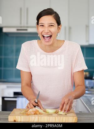 Ist jemand, der hier Zwiebeln schneidet. Eine junge Frau, die eine Zwiebel schneidet. Stockfoto