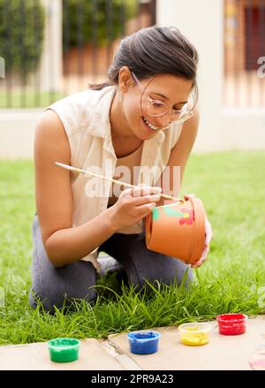 Phantasie ist der Anfang der Schöpfung. S junge Frau malen einen Topf im Garten zu Hause. Stockfoto