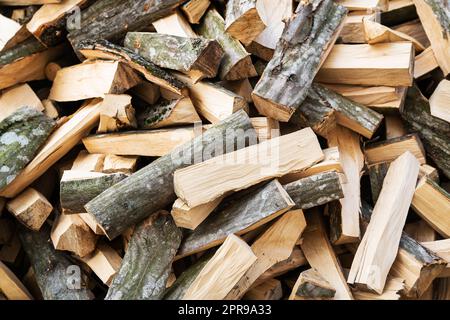 Brennholzbestand für die Heizung des Hauses. Die Bäume wurden gefällt und in Brennholz geteilt, um sie als Brennstoff in Kamin und Öfen zu verwenden, mit einem Hintergrund aus Brennholz. Stockfoto