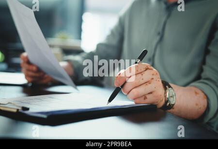 Ich muss nur dieses Formular unterschreiben. Ein unkenntlich Geschäftsmann, der Papierkram in einem Büro bei der Arbeit macht. Stockfoto