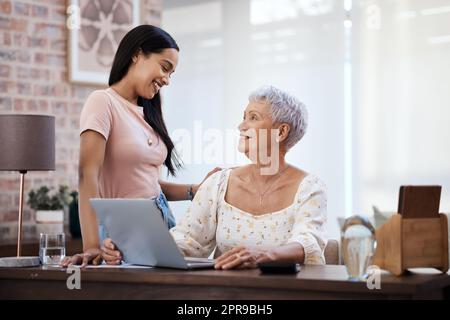 Mama, eine junge Frau, die mit ihrer älteren Mutter einen Laptop benutzt, während sie zu Hause die Finanzen durchläuft. Stockfoto