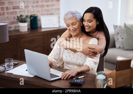 Ein gut geplanter Ruhestand sorgt für eine süße Rückkehr. Eine junge Frau, die mit ihrer älteren Mutter einen Laptop benutzt, während sie zu Hause die Finanzen durchläuft. Stockfoto